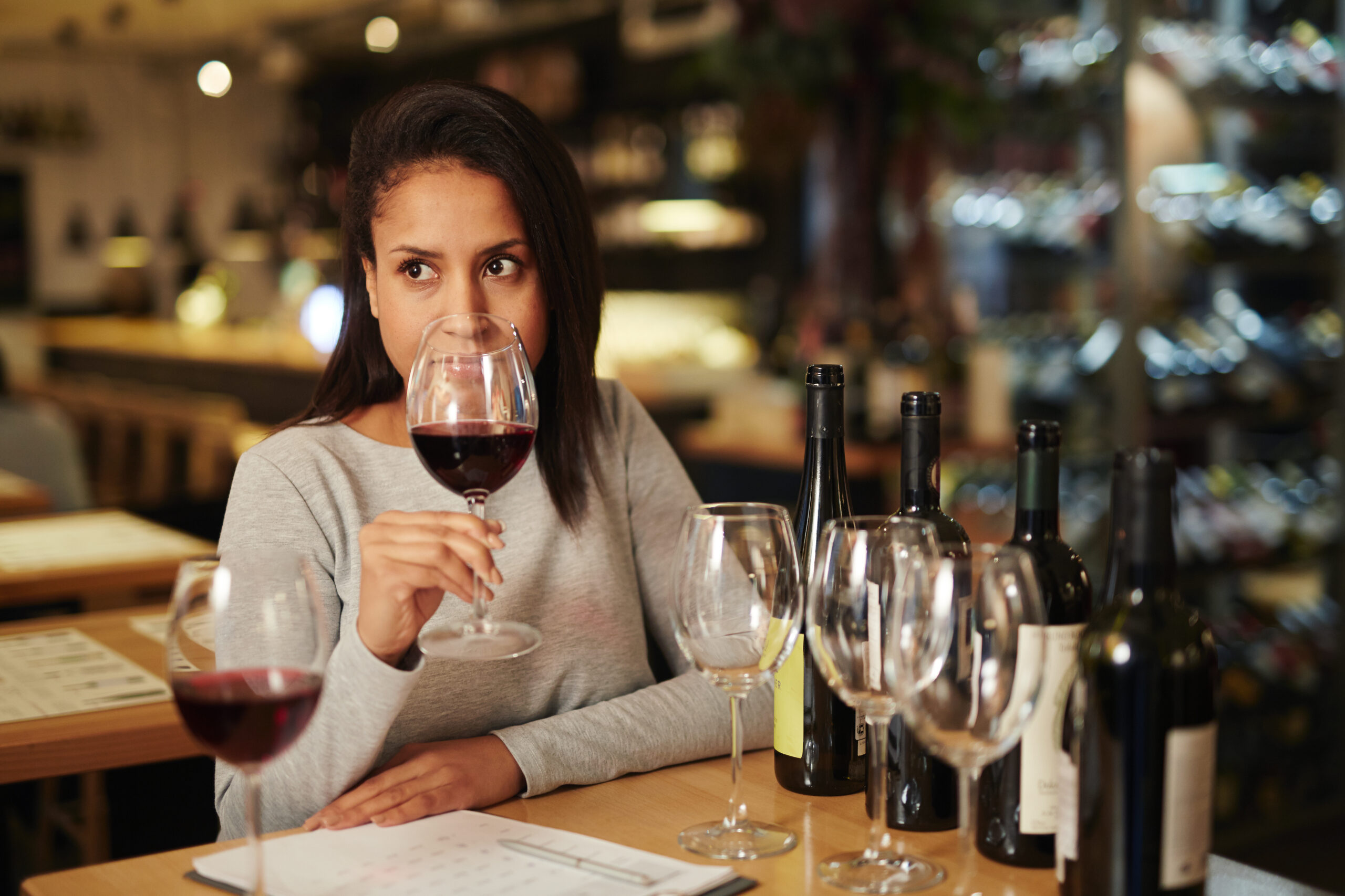 Mostra uma pessoa sentada provando taças de vinho.