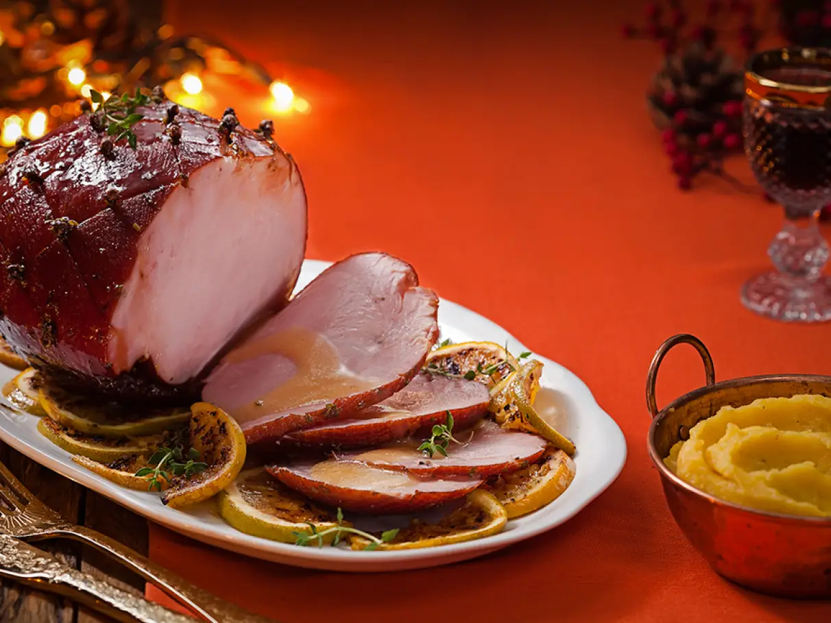 Tender ao molho de laranja decorado com ervas frescas e acompanhado de frutas cítricas.