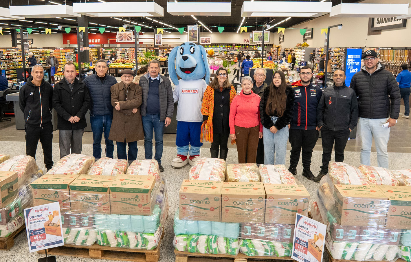 Representantes das entidades sociais beneficiadas ao lado da diretoria do Super Andreazza na nova loja de São Leopoldo, com as toneladas de alimentos doados pela campanha Baixou, Doou em destaque.